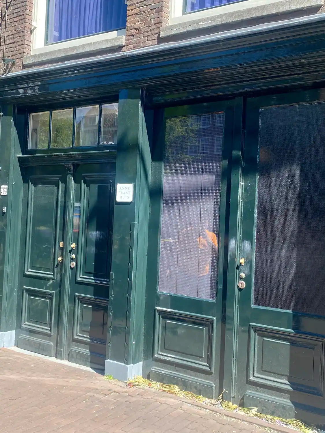 A dark green painted frontage with doors and windows and a small plaque, seen from the pavement.