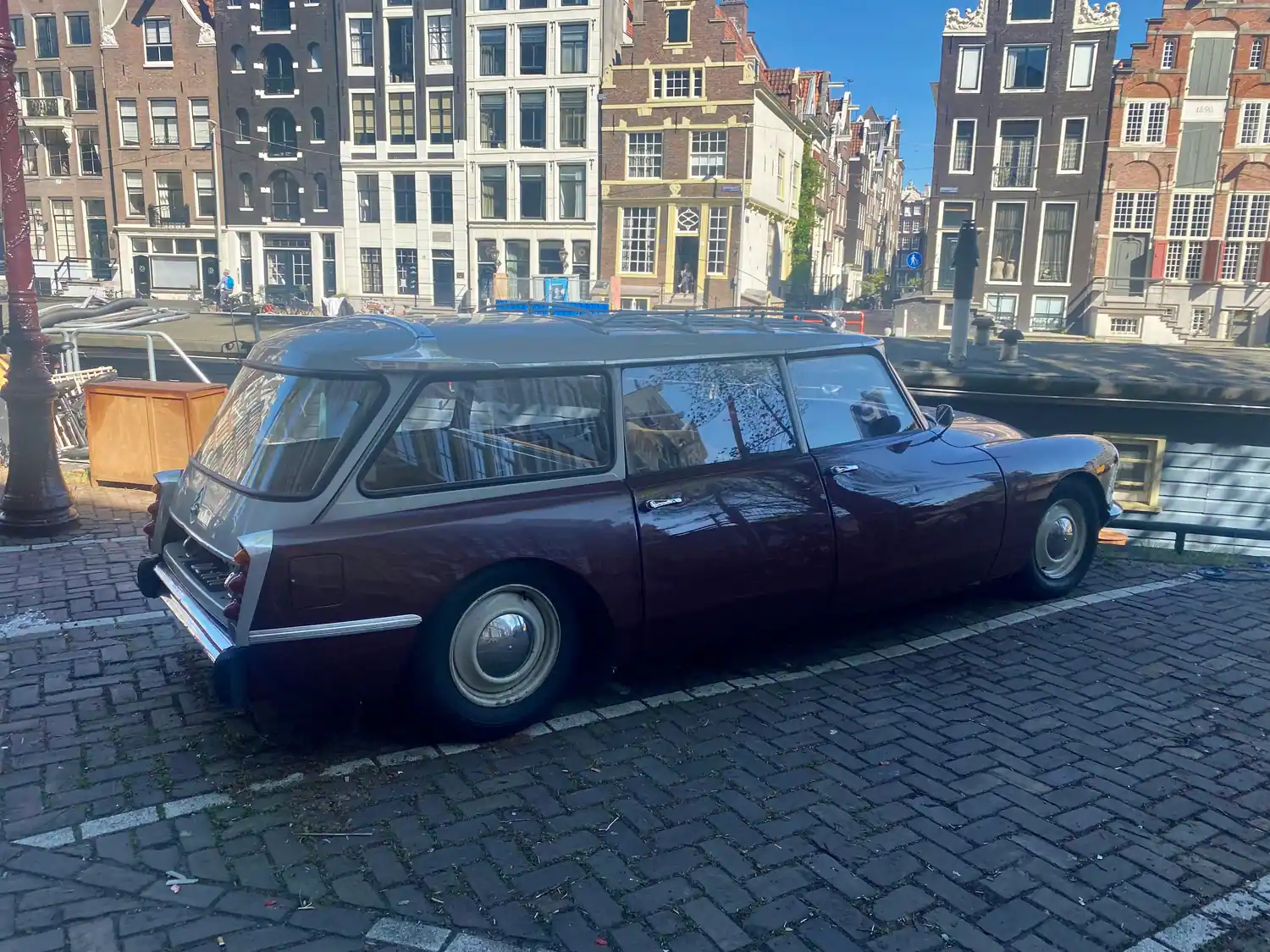 An old maroon estate car parked on cobbles in front of a terrace of houses.
