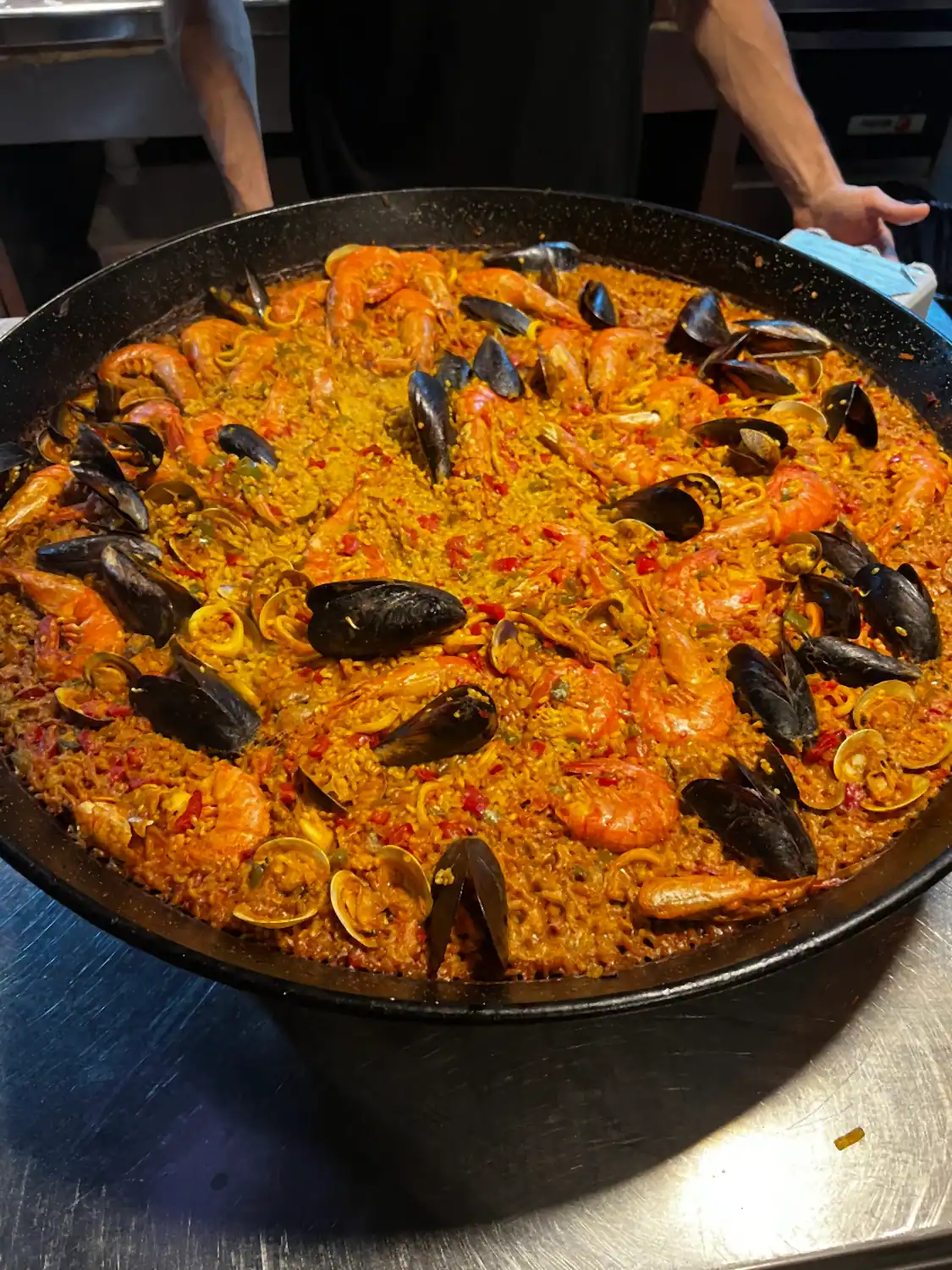 A wide pan of rice with mussels and shellfish in their shells across it.