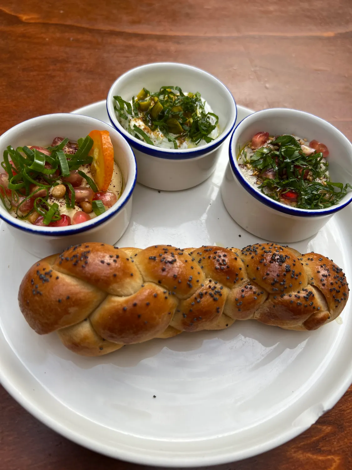 Three small bowls of dressed salad on a table, a coiled pastry on a plate in front of them.