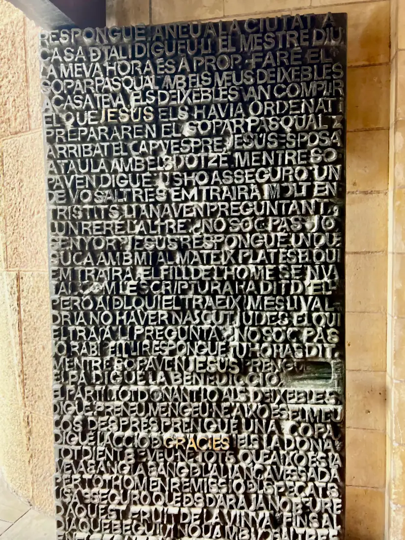 A tall stone panel carved all over with rows of lettering beside a stone doorway.