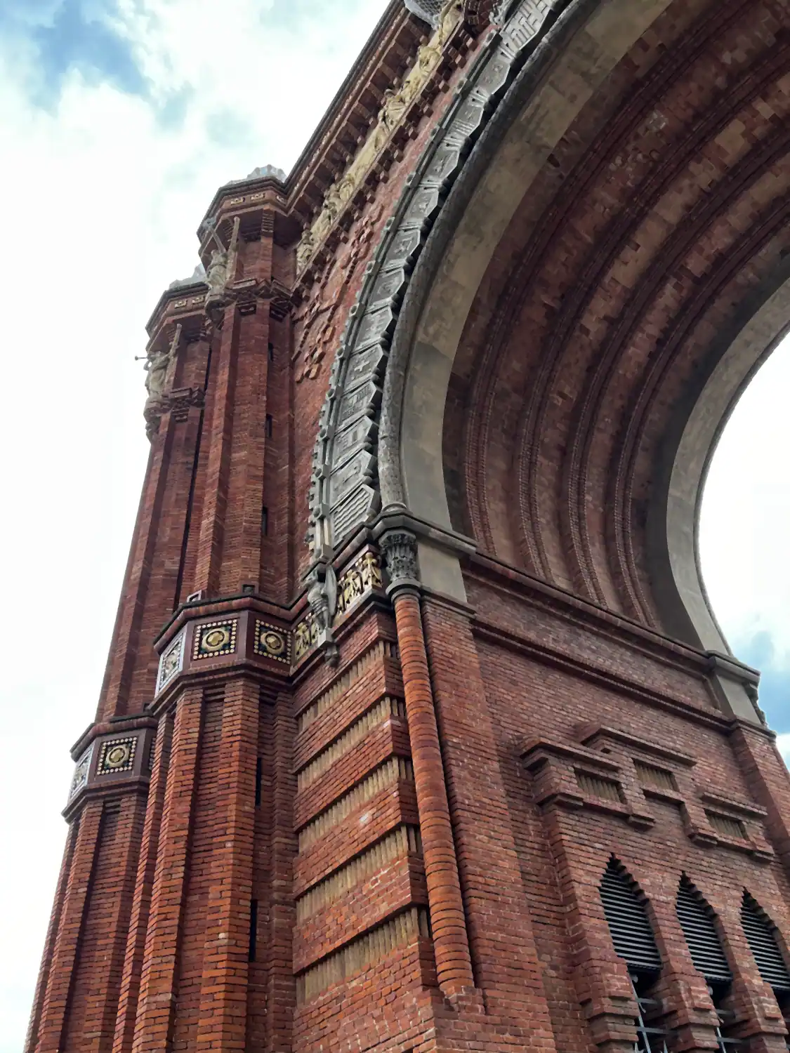 The underside of a brick arch seen from below, its courses and a carved panel running up out of frame.