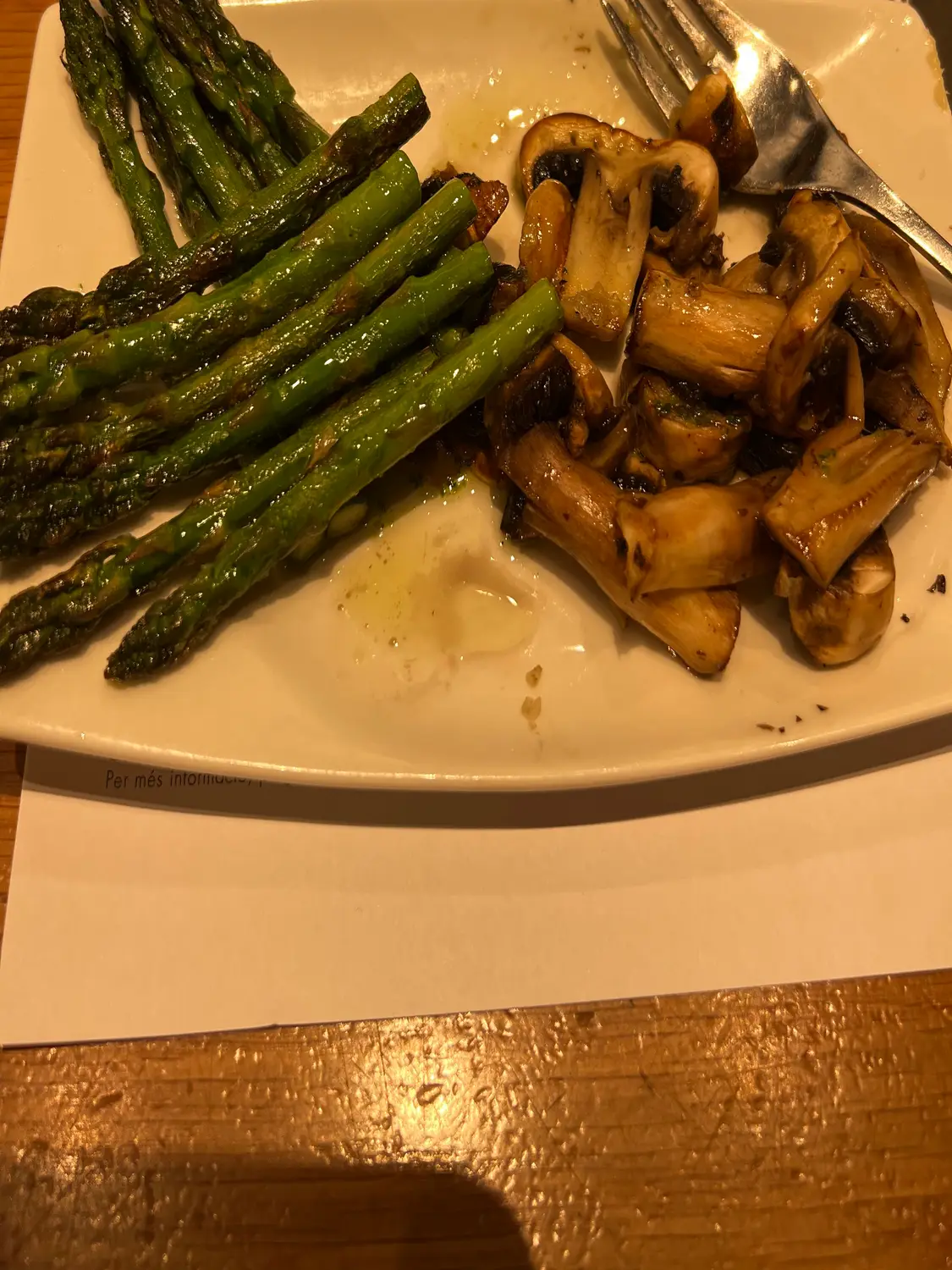 Grilled green spears and sliced mushrooms on a plate on a table.