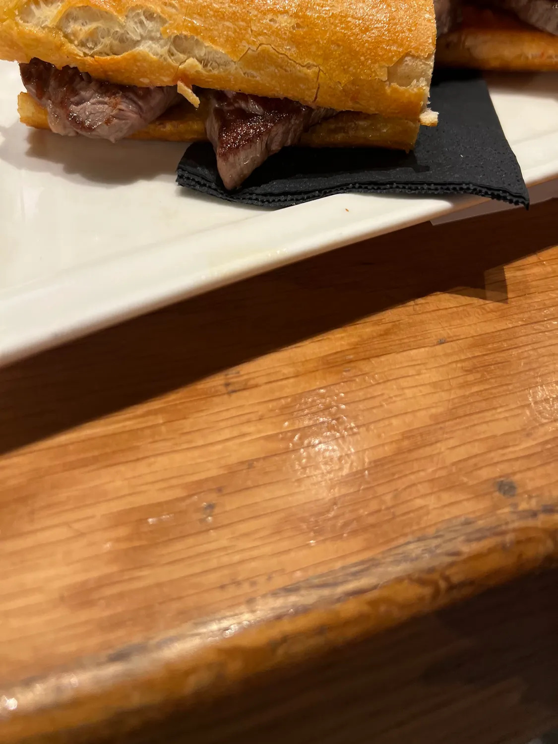 A long roll of pastry on a board with a small glass of drink beside it.