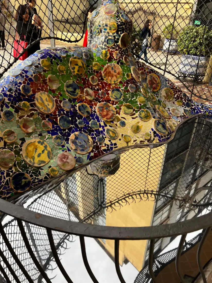 A wall of small round mosaic pieces behind a rope net, each one a different picture.