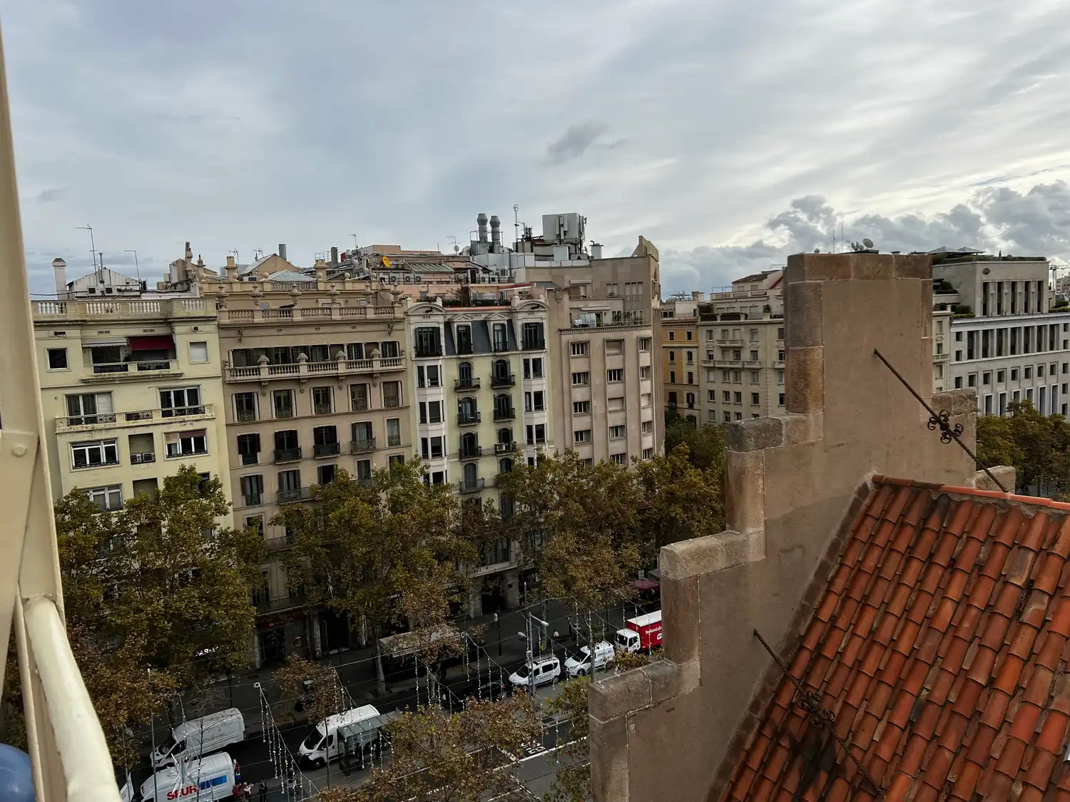 City rooftops and a street of traffic seen across a tiled roof from a terrace.