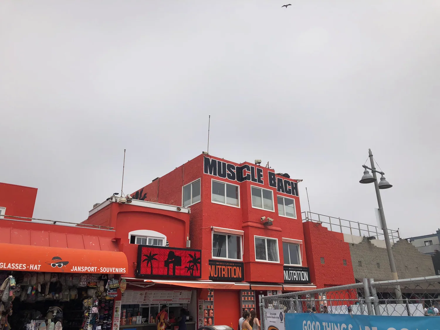 A red and white building with shopfronts along a beachfront under a clear sky.