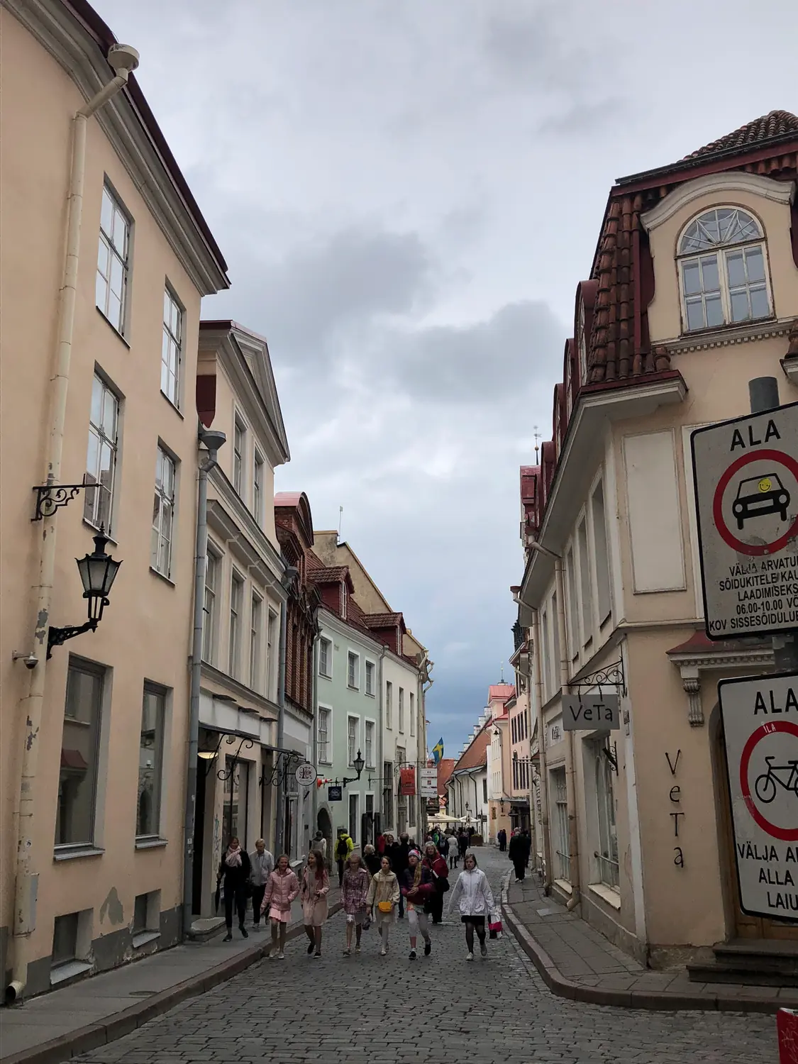 A street of old houses with two no entry signs and people walking away.