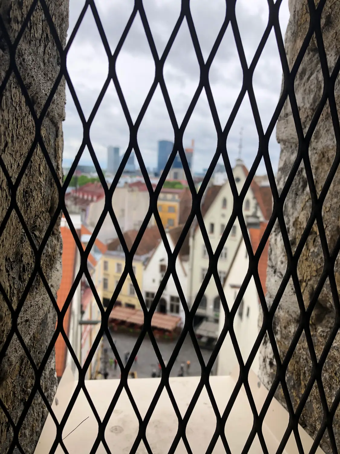 An old town seen through a grid of iron bars in a window.