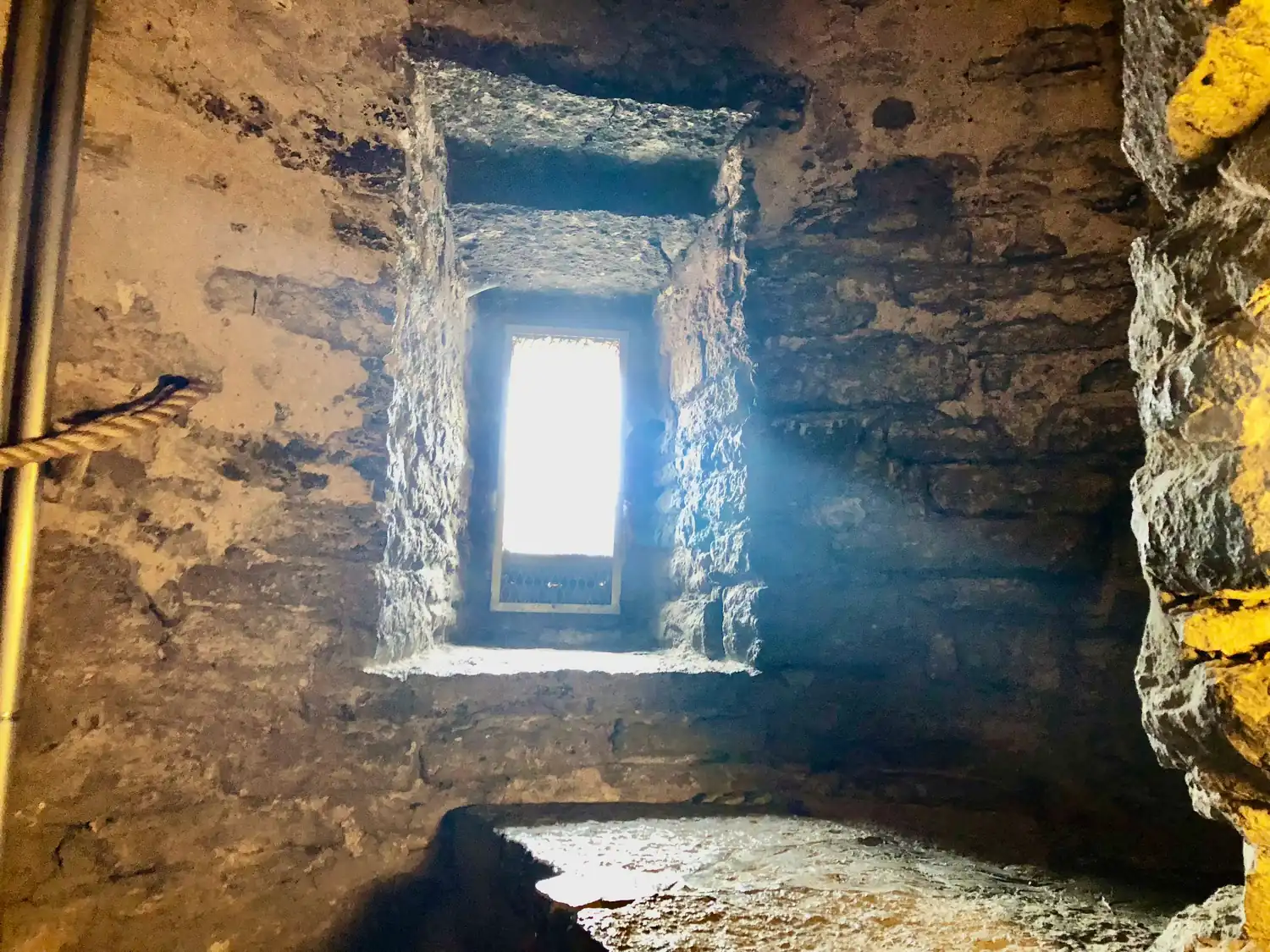 A deep set window in a stone wall, lit from outside.