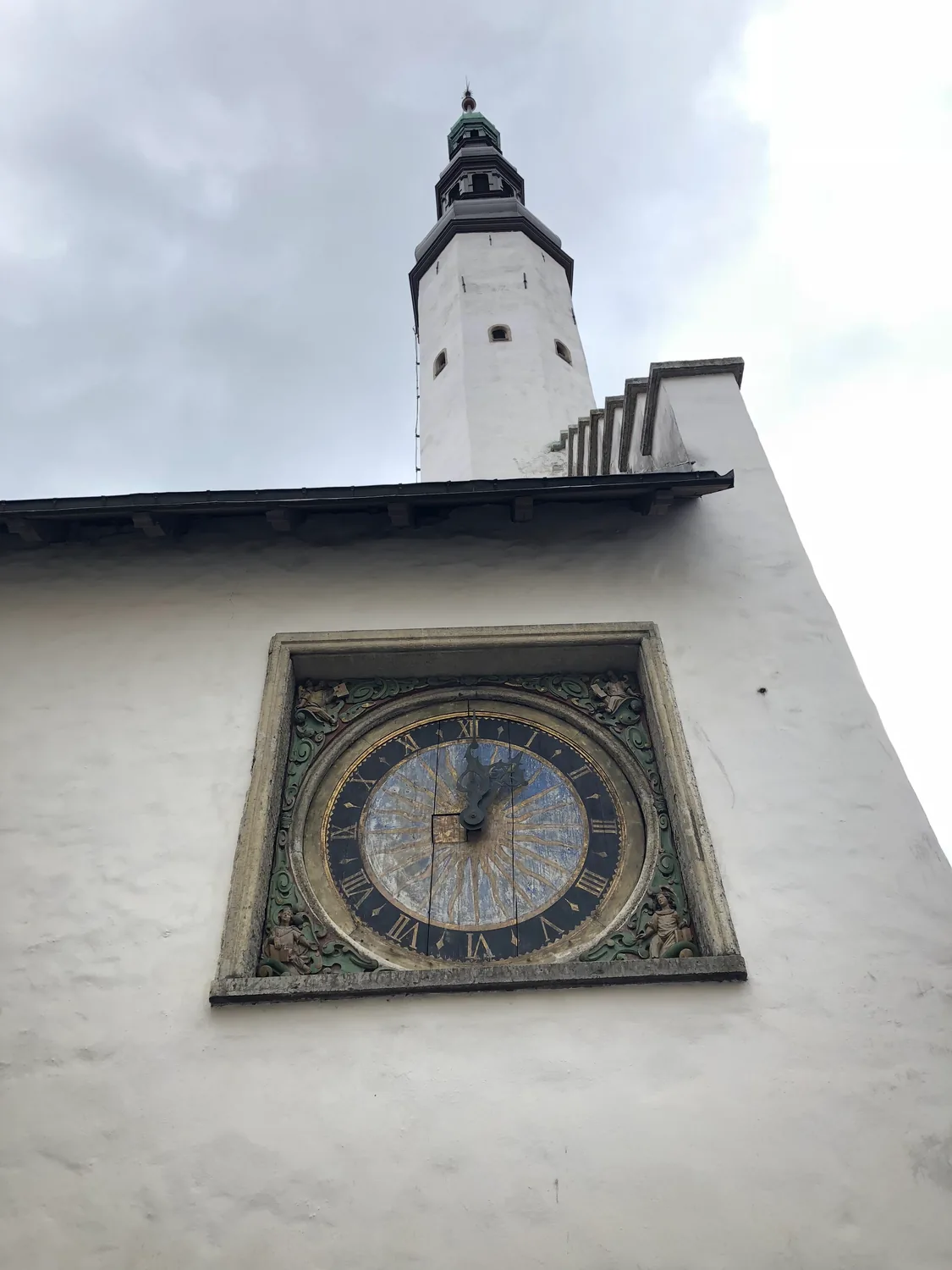 A wall dial with a tower standing above it.