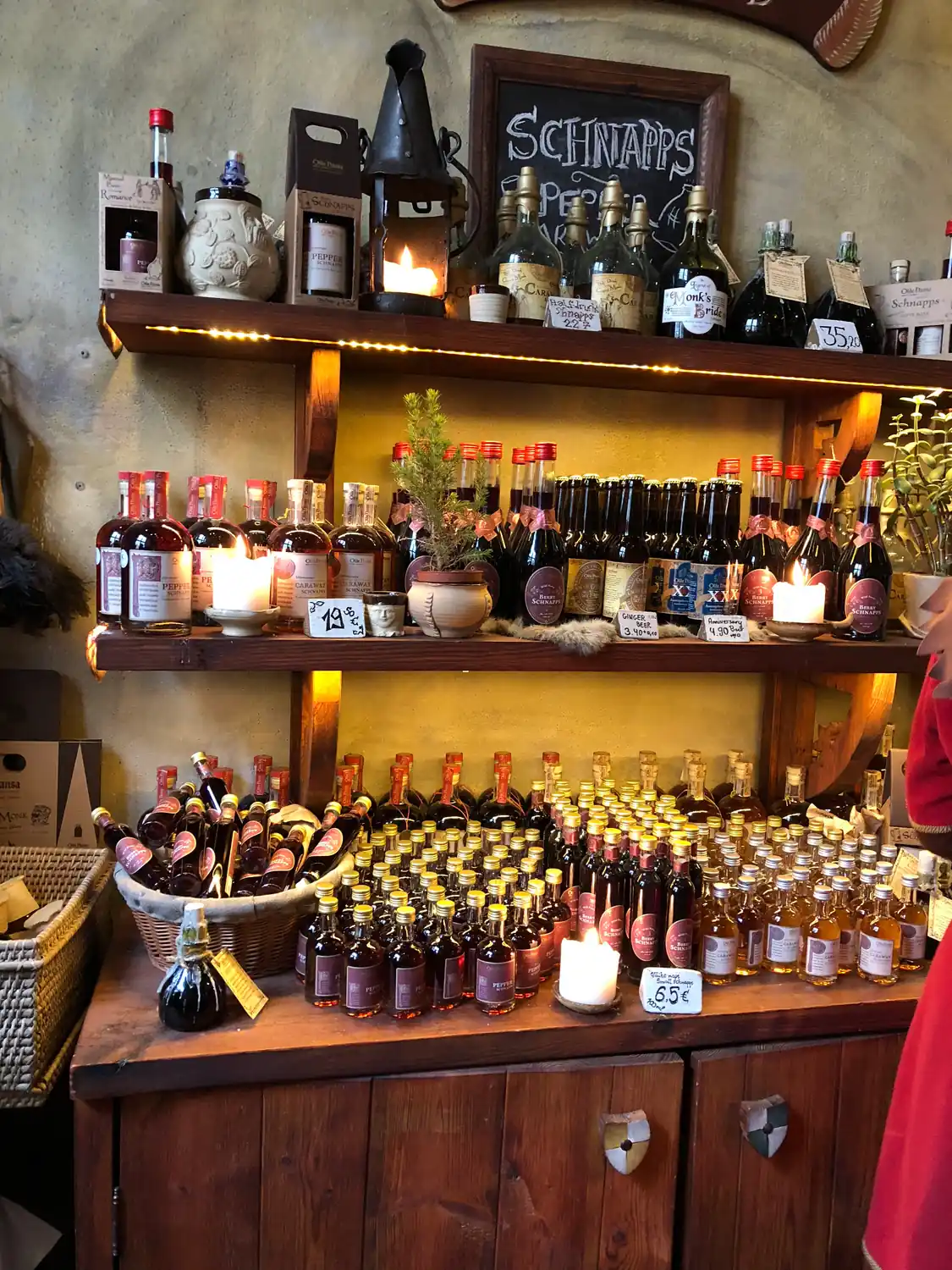 Shelves of small bottles over a shop counter with a small written board above them.