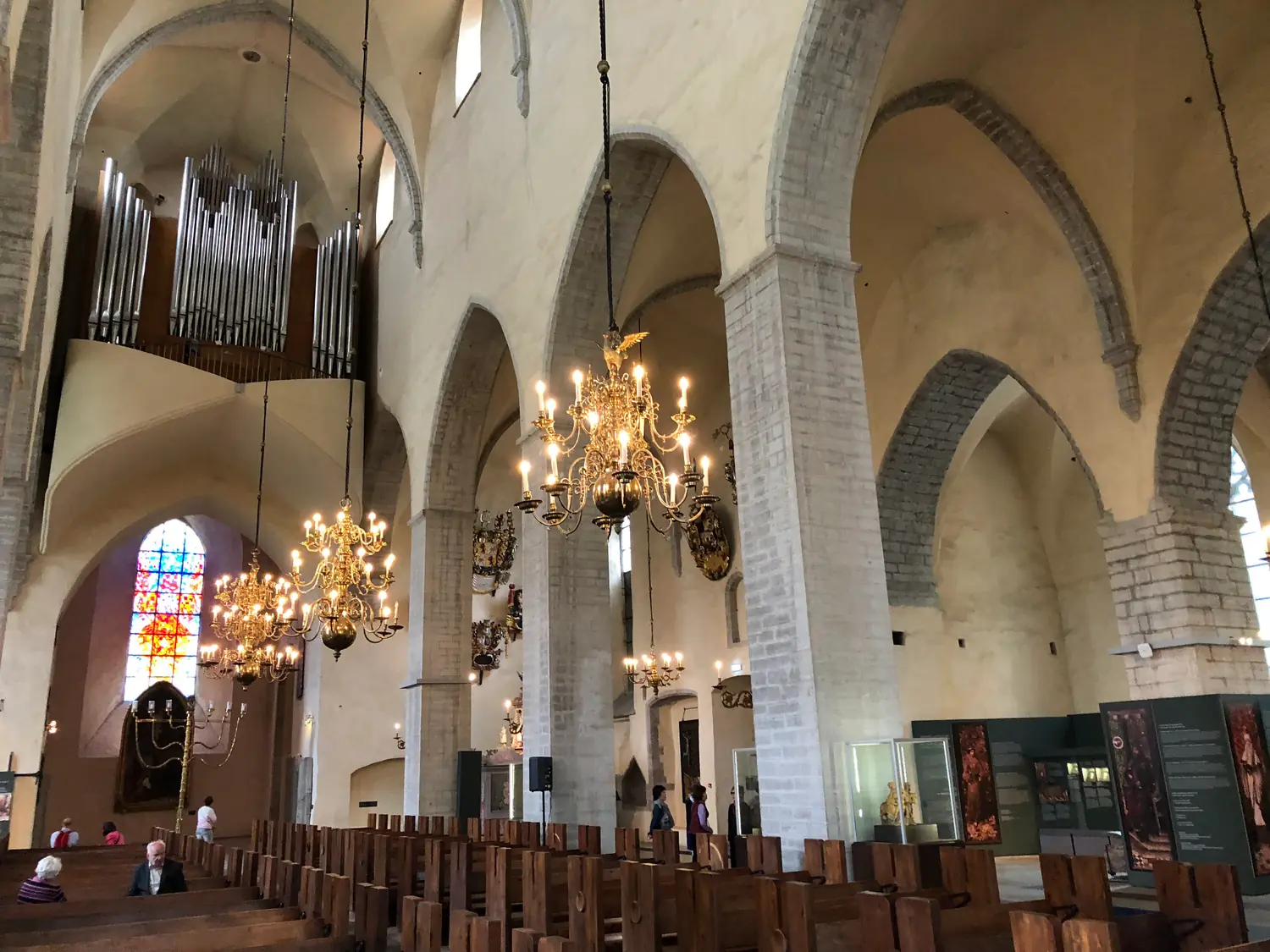 The inside of a church, its arches, pews and hanging lights.