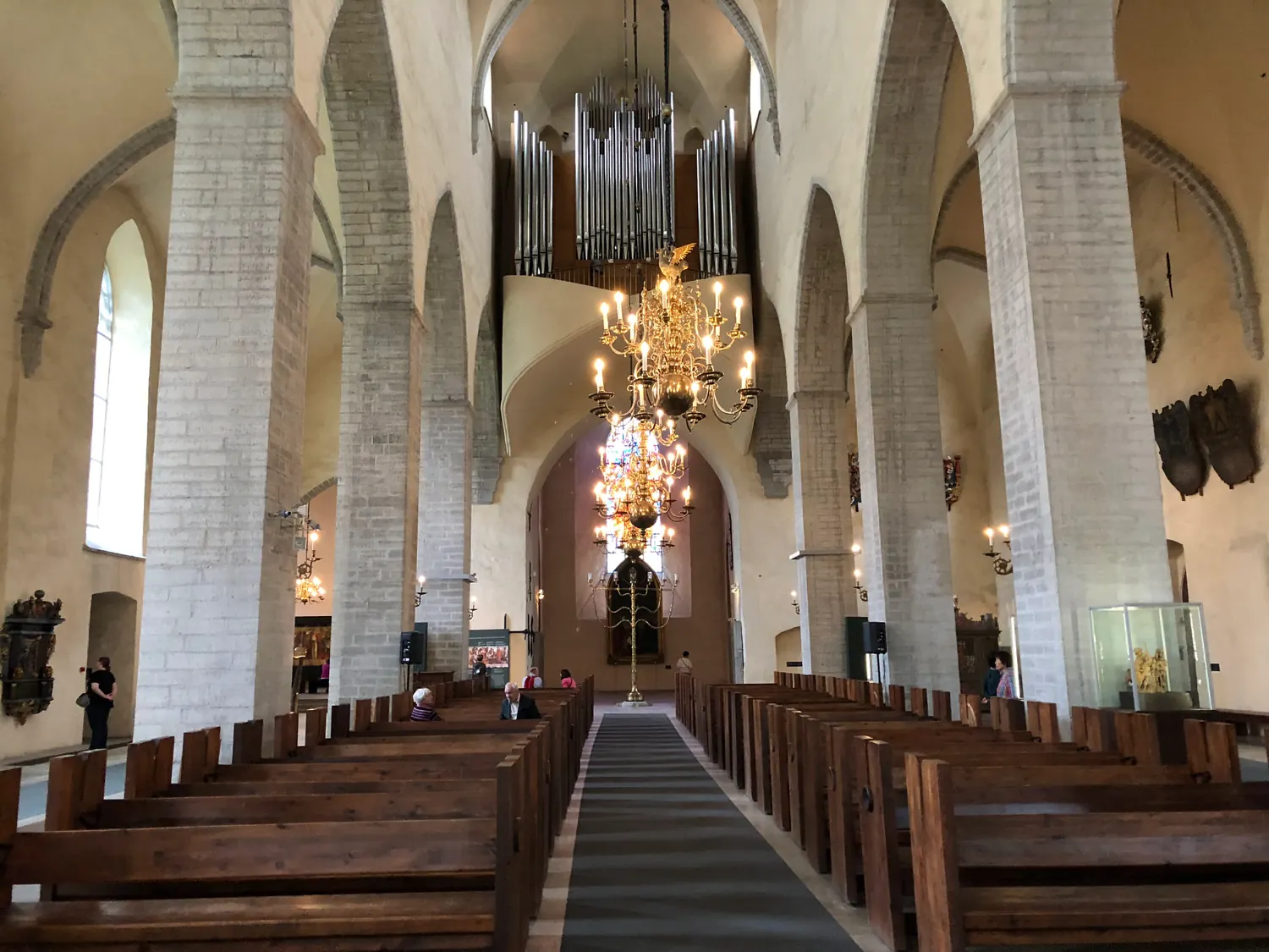 A church aisle with its hanging lights and the altar beyond.