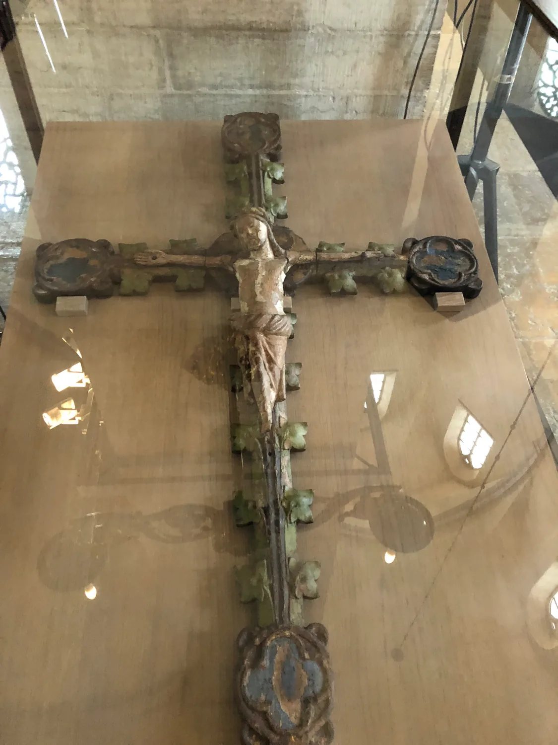 A carved crucifix under glass on a display table.