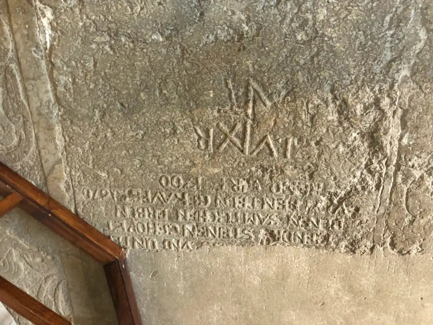A carved stone slab with lettering set in a wall and a step below it.
