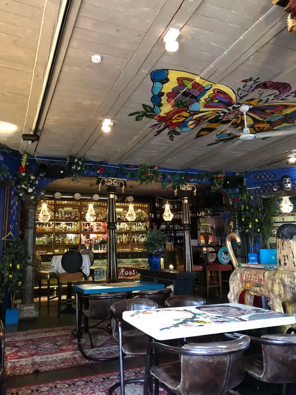 The inside of a cafe with a painted ceiling panel, tables and a service counter.