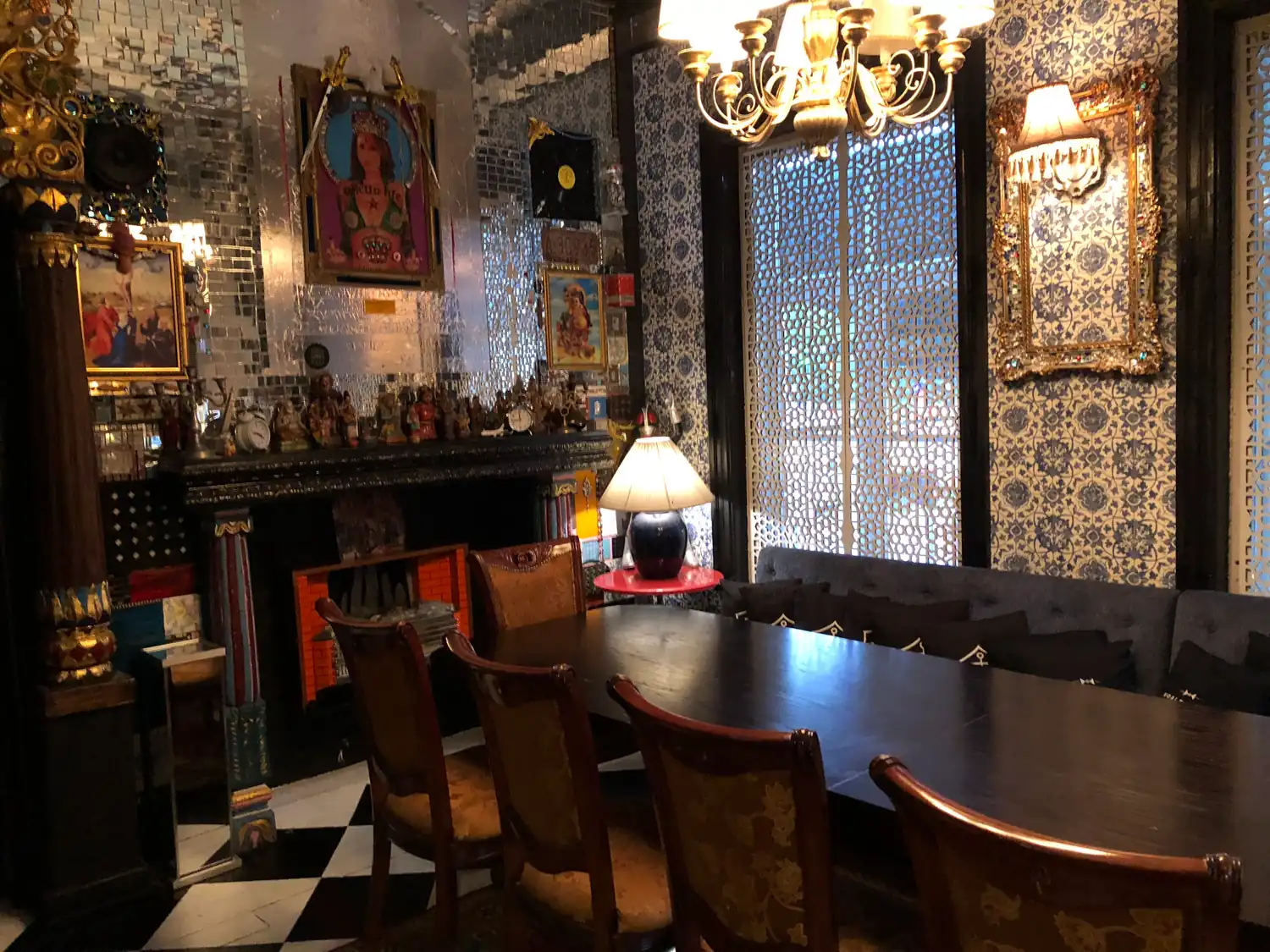 A long table and chairs in a room whose walls carry framed pictures and objects.