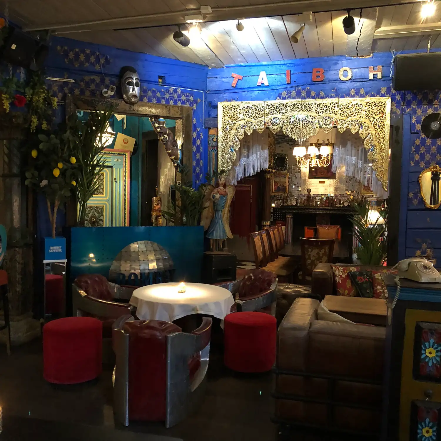A room with blue walls, a name spelled in letters over an arch, armchairs and stools.