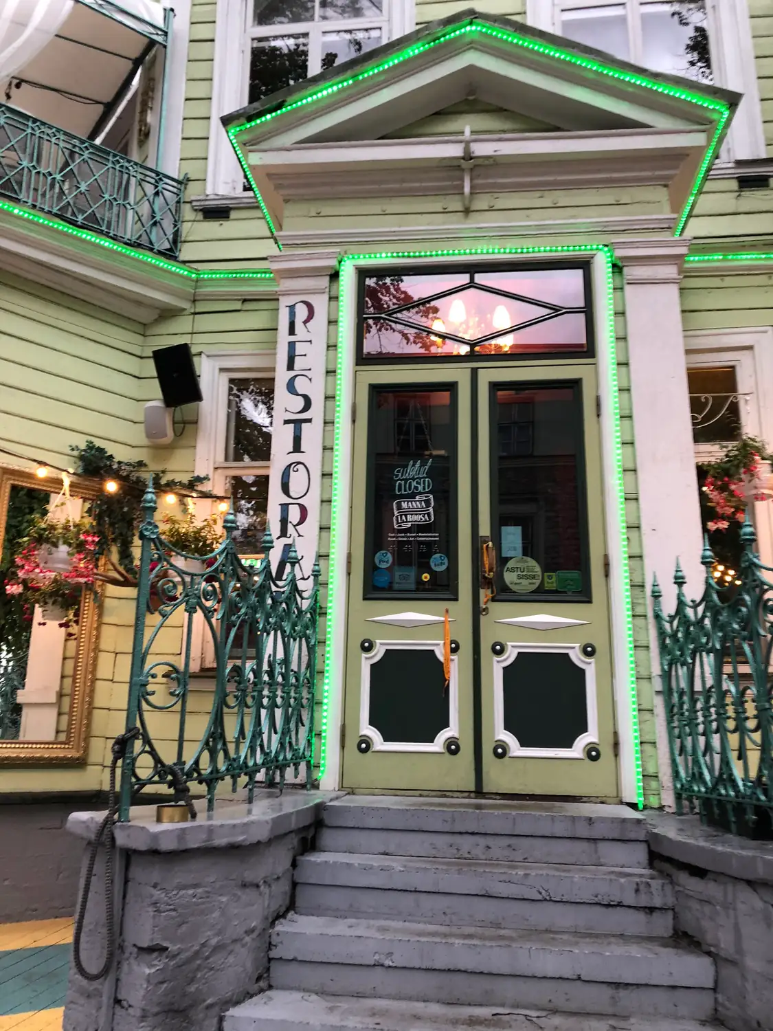 A lit doorway of a building with green painted trim and a sign beside it.