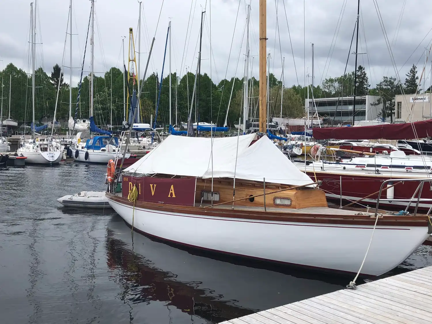 A marina of moored yachts with a varnished wooden launch in the foreground.