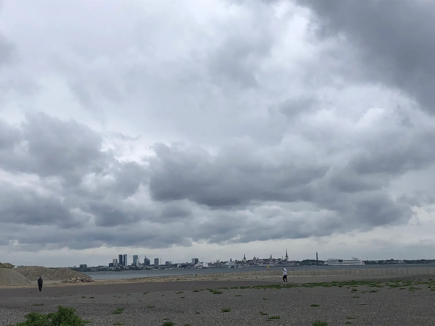 A shingle beach with a distant skyline across the water.