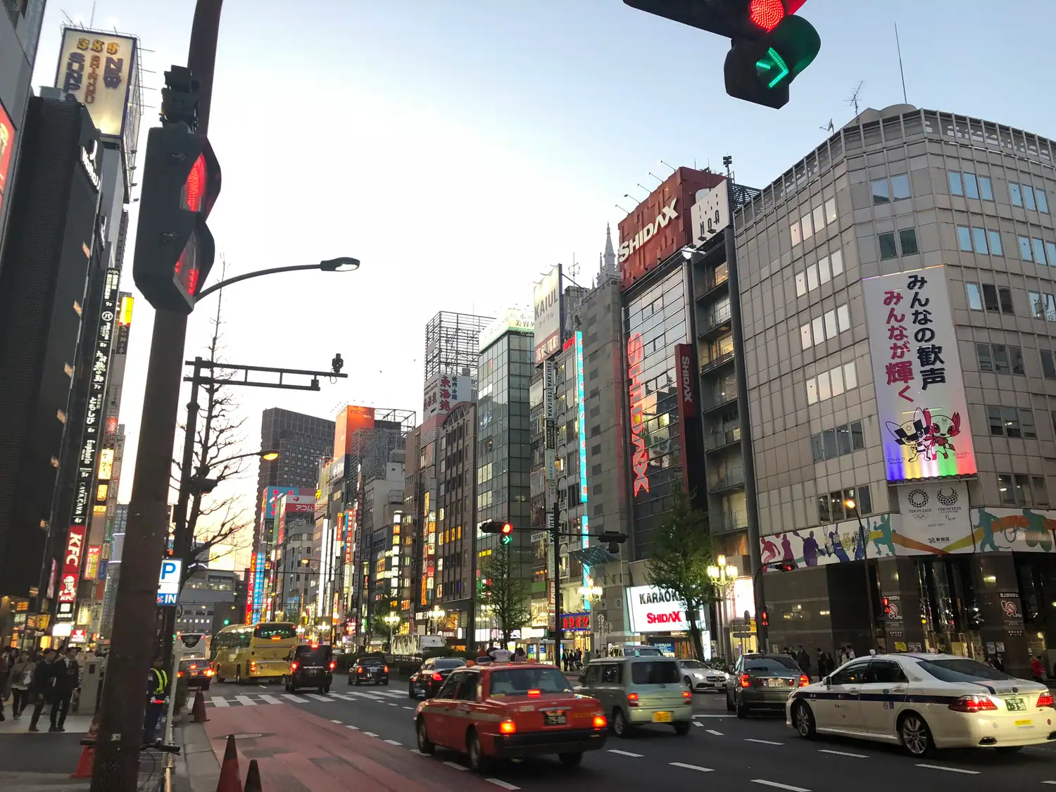 A crossing with taxis and traffic lights, buildings rising beyond the road.
