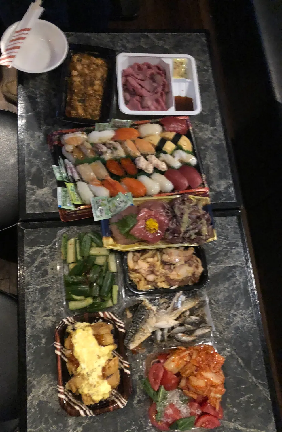 A boxed meal of many small dishes laid out in their trays on a table.