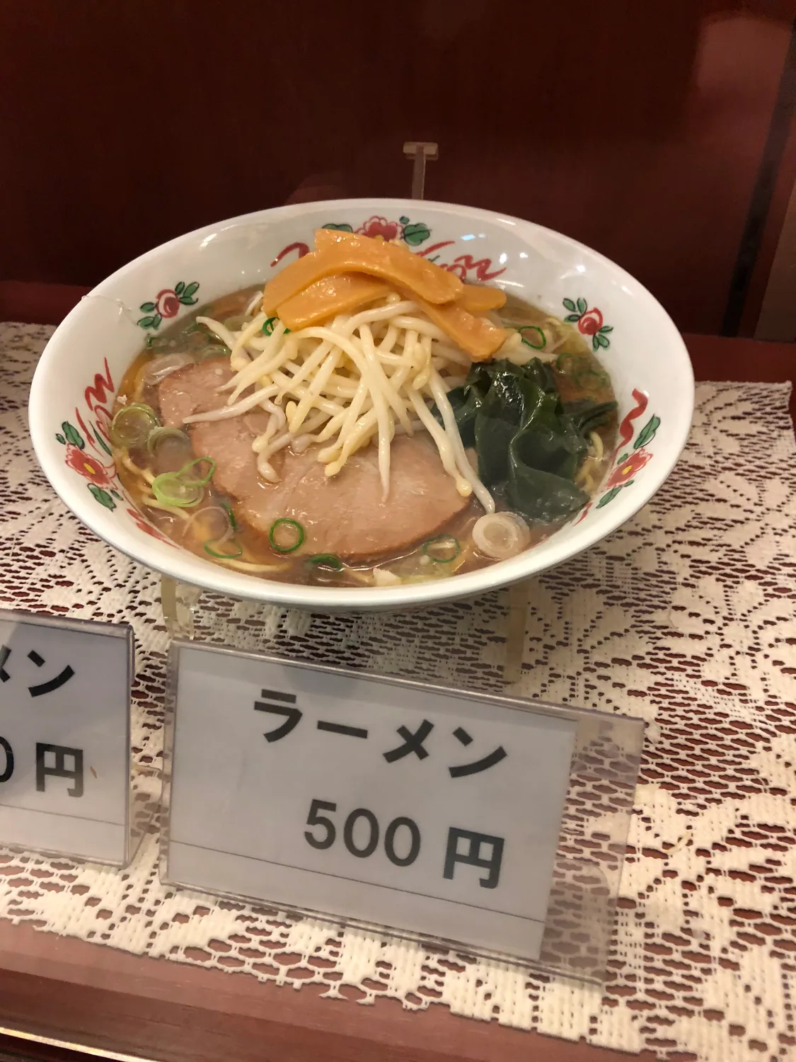 A bowl of noodles on a table with a printed card standing beside it.