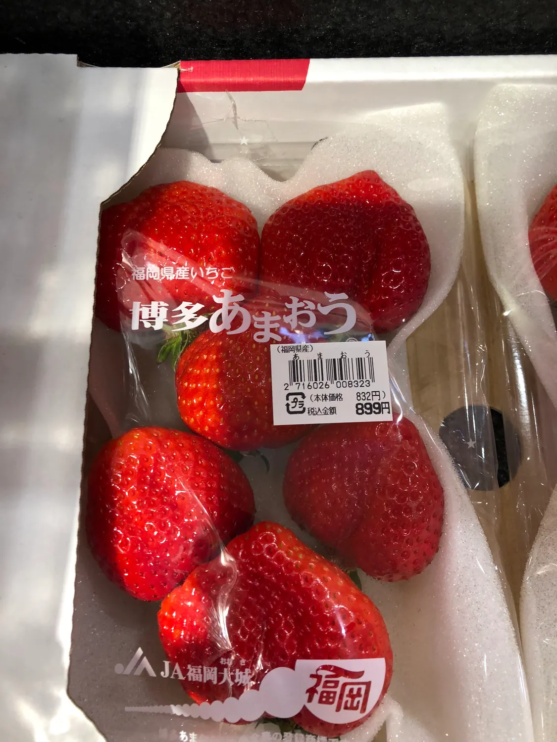 A sealed punnet of strawberries under film with a printed label across the lid.