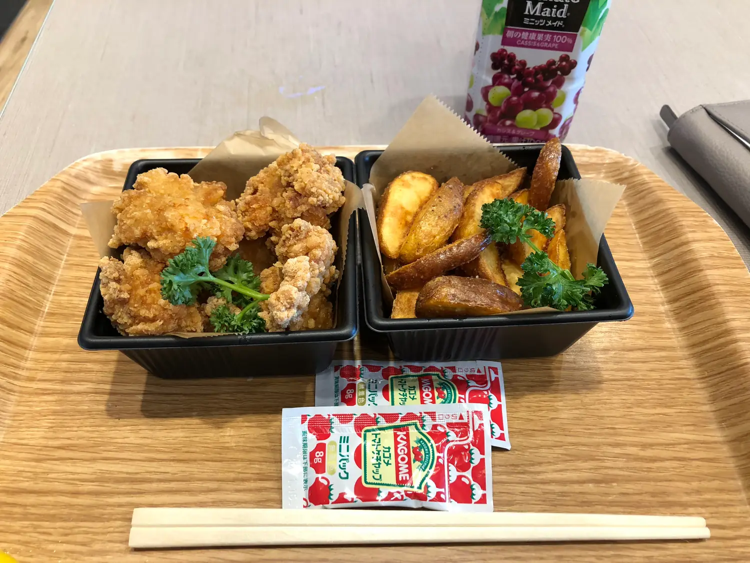 Takeaway fried food in two boxes on a tray with a drink and a card beside them.